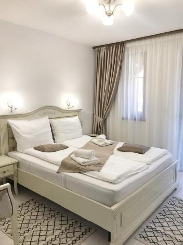 a large white bed in a bedroom with a window at Pensiunea ARMONIA in Văleni