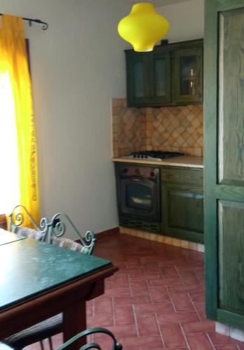 a kitchen with green cabinets and a table and a stove at Violivia in Aggius