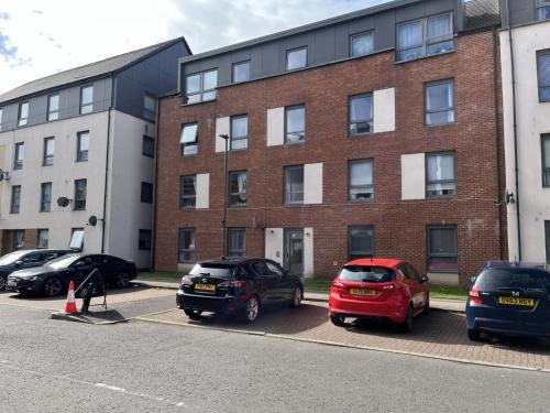 a parking lot with cars parked in front of a building at Bright 2 Bedroom Apartment - Edinburgh in Edinburgh