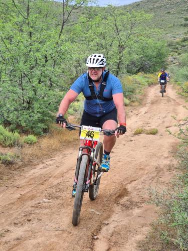 un hombre montando una bicicleta en un camino de tierra en African Game Lodge, en Montagu