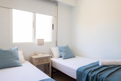 2 Betten in einem Zimmer mit 2 Fenstern in der Unterkunft FLORIT FLATS - The Xeraco Beach Frontline Apartment in Xeraco