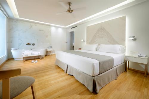 a bedroom with a large bed and a bath tub at Talayot - Adults Only in Cala Millor