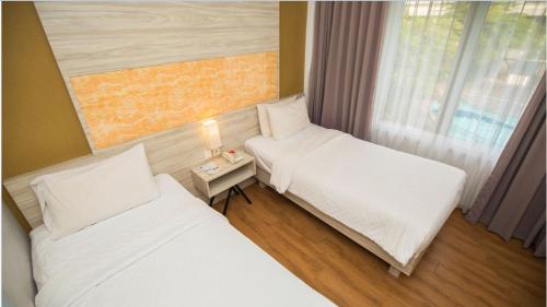 a room with two beds and a window at Front One Akshaya Hotel Karawang in Karawang