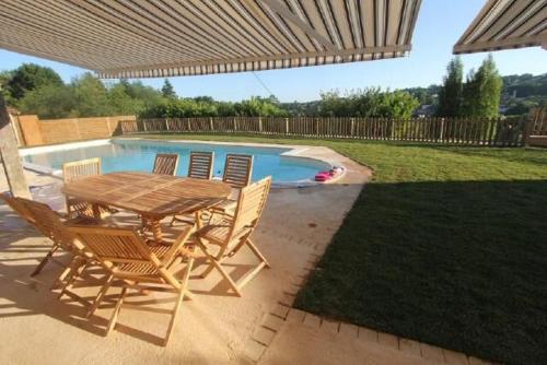 - une table et des chaises sous un parasol à côté de la piscine dans l'établissement La Salamandrine, à 600 m du centre historique par un sentier, à Sarlat-la-Canéda