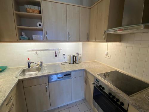 - une cuisine avec des placards blancs et un évier dans l'établissement Apartment am See Bad Saarow, à Bad Saarow