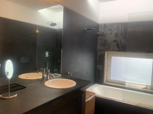 ein Badezimmer mit zwei Waschbecken, einer Badewanne und einem Fenster in der Unterkunft Villa do Val Seixas - Piscina Privada in Seixas