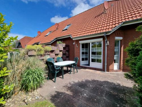 a patio with a table and chairs in front of a house at Ferienhaus Claudia in Norden
