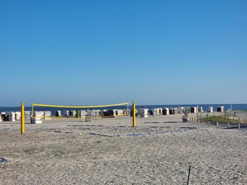 a beach with yellow poles in the sand and the ocean at Ferienhaus Claudia in Norden