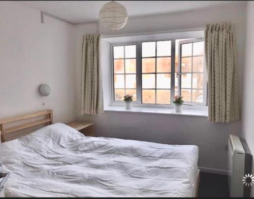 a bedroom with a white bed and two windows at Great price, lovely comfy flat.2 mins from the sea in Lyme Regis