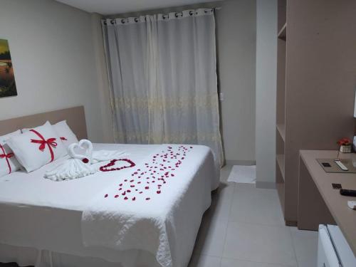 a bedroom with a white bed with red roses on it at Hijo Buriti Hotel in Mauriti