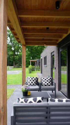 a patio with two couches and a table with pillows at The Black Oak - Luxe bungalow met prive sauna in Voorthuizen