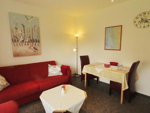 uma sala de estar com um sofá vermelho e uma mesa em Haus Dithmarschen Wohnung 2 em Büsum