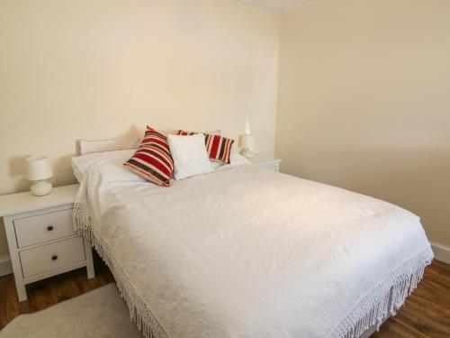 a white bed with two pillows on top of it at 7 Cummertrees in Annan