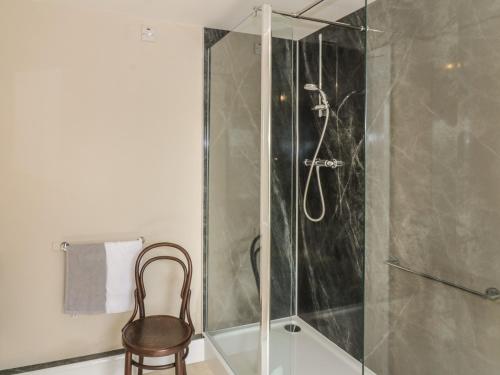 a glass shower with a chair in a bathroom at 7 Cummertrees in Annan