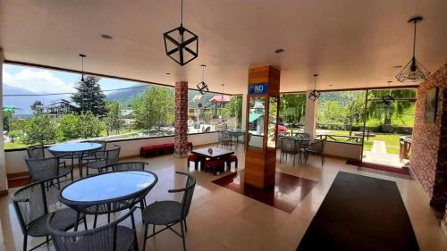 a restaurant with tables and chairs and a large window at vella Mrina Group of hotel Manali in Manāli