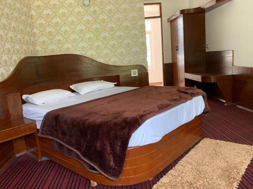 a bedroom with a large bed with a wooden headboard at vella Mrina Group of hotel Manali in Manāli