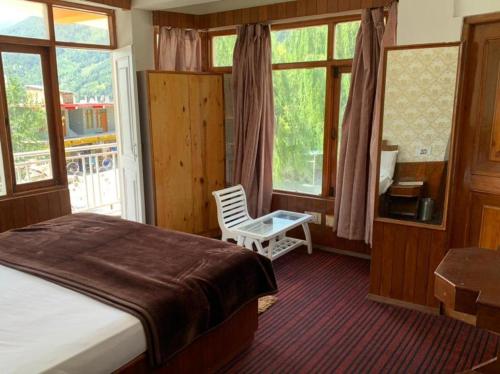 sypialnia z łóżkiem, krzesłem i oknami w obiekcie vella Mrina Group of hotel Manali w mieście Manāli