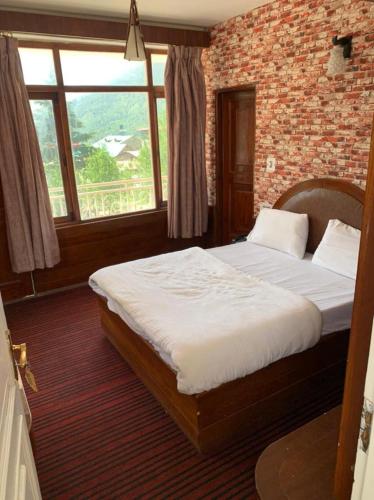 a bedroom with a large bed with a brick wall at vella Mrina Group of hotel Manali in Manāli