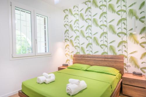 ein Schlafzimmer mit einem grünen Bett und Handtüchern darauf in der Unterkunft Villa Acquario - Giardino - 200 mt dalla spiaggia in Torre delle Stelle