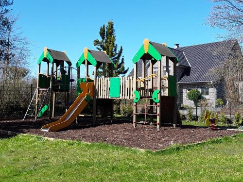a playground in a yard with a slide and a slope at Ferienwohnung im Palais Rosenlund in Hürup