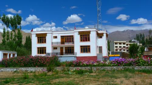 a white house with flowers in front of it at Orion Home in Leh