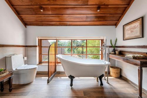 a bathroom with a tub and a toilet and a window at Evolve Back Coorg in Siddapur