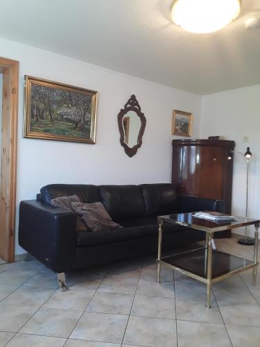 a living room with a black couch and a table at Ferienwohnung im Palais Rosenlund in Hürup