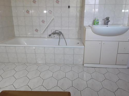 ein weißes Badezimmer mit einer Badewanne und einem Waschbecken in der Unterkunft Ferienwohnung im Palais Rosenlund in Hürup