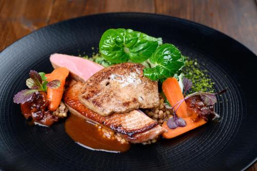 a plate of food with meat and vegetables on a table at Parizs Garden Apartments in Debrecen