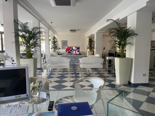 a lobby with a desk with a computer and chairs at Hotel Athena in Lignano Sabbiadoro