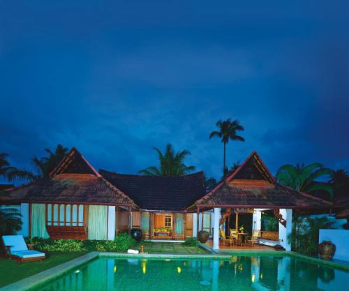 a villa with a swimming pool at night at Kumarakom Lake Resort in Kumarakom