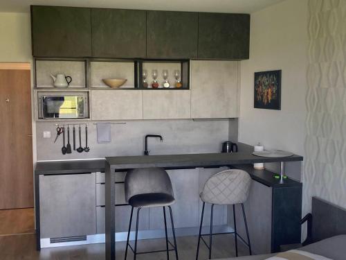 a kitchen with two bar stools and a counter top at Sunset Studio Apartment in Poprad