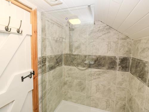 a shower with a glass door in a bathroom at Bwthyn Siop Pencaerau in Pwllheli