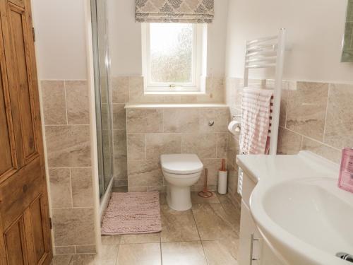 a bathroom with a toilet and a sink and a window at Crag View Cottage in Skipton