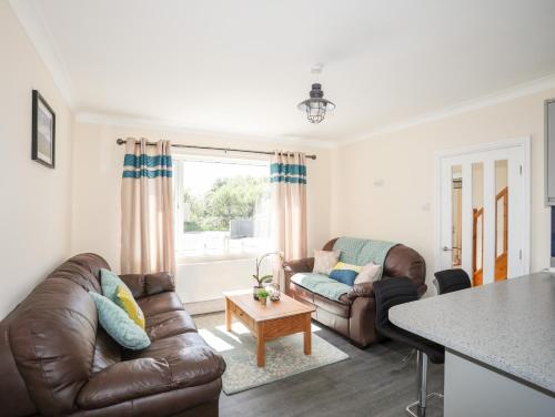 a living room with two leather couches and a table at Glan Aber in Pwllheli