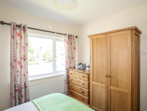 a bedroom with a dresser and a window at Glan Aber in Pwllheli