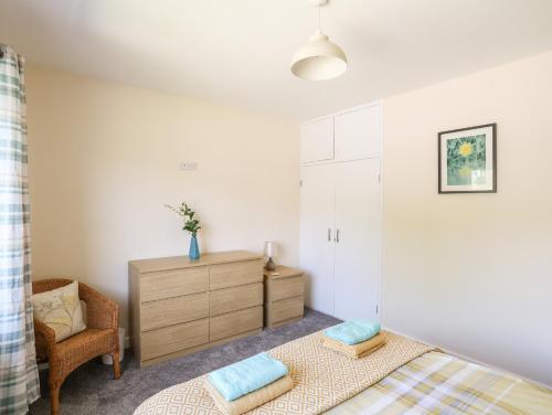 a bedroom with a bed and a dresser and a chair at Glan Aber in Pwllheli