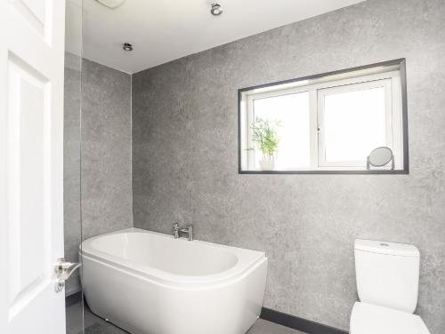 a bathroom with a tub and a toilet and a window at Glan Aber in Pwllheli