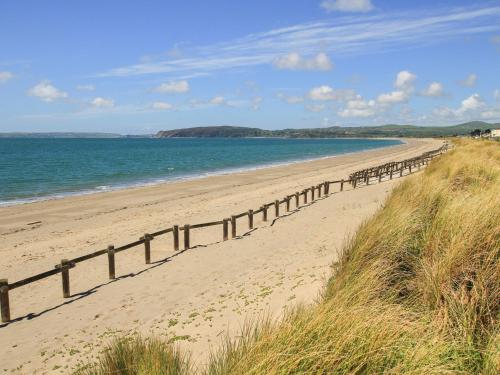 a sandy beach with a fence on it next to the ocean at Glan Aber in Pwllheli