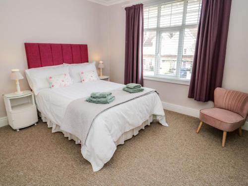 a bedroom with a bed and a chair and a window at 3 St Davids Place in Llandudno