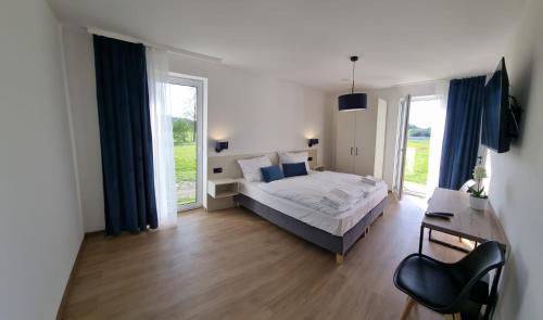 a bedroom with a bed and a desk and windows at Apartamenty Boczna 3B z sauną i balią in Kudowa-Zdrój