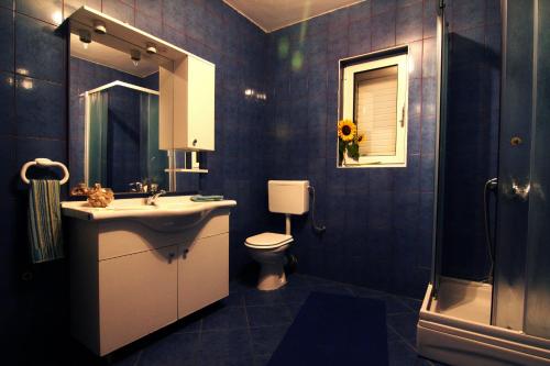 ein blau gefliestes Bad mit einem Waschbecken und einem WC in der Unterkunft Apartments Nebeska in Novalja