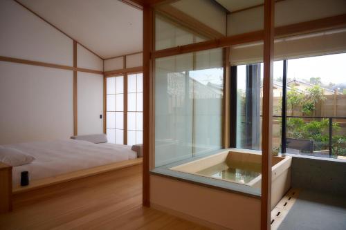 a bedroom with a tub and a bed and a window at Azumi Setoda in Onomichi