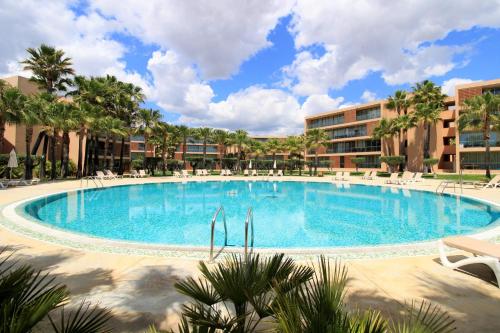 a large swimming pool with palm trees and buildings at Albufeira Salgados Premium 1 With Pool by Homing in Guia