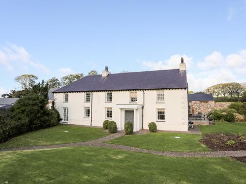 a large white house with a large yard at Clynnog House in Dwyran