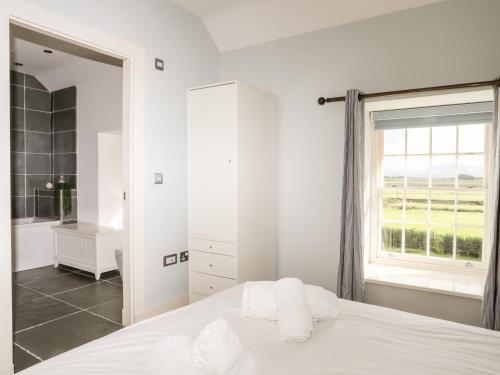 a white bedroom with a large window and a bed at Clynnog House in Dwyran