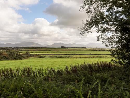 a green field with mountains in the distance at Clynnog House in Dwyran