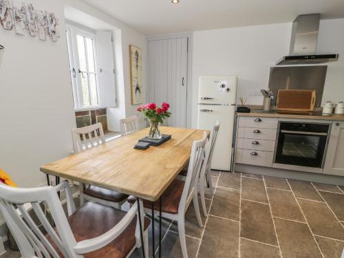 a kitchen with a wooden table with flowers on it at Swn yr Afon in Caernarfon