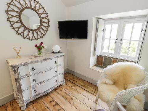 a room with a dresser and a mirror and a chair at Swn yr Afon in Caernarfon