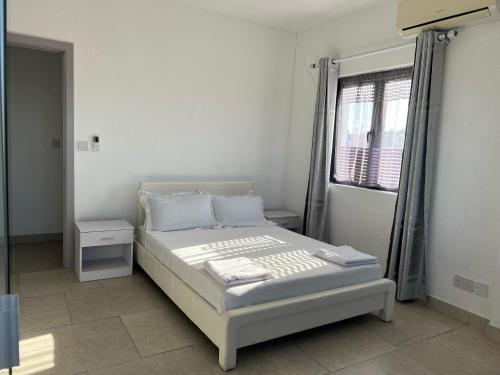 a white bedroom with a bed and a window at Ibis Tourist Residence 1 in Mahébourg